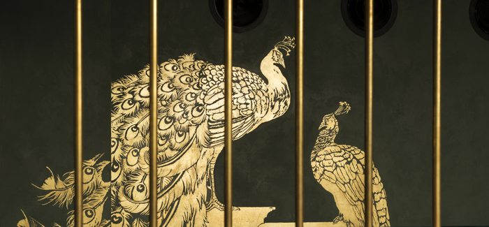 Abe’s peacocks, two monumental statues of gold-leaf behind brass vault bars.